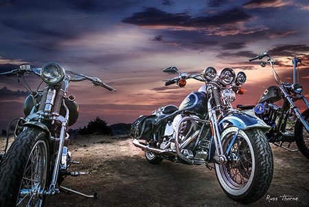 Three custom Harley-Davidson motorcycles displayed against a stunning sunset, showcasing their unique designs and craftsmanship.